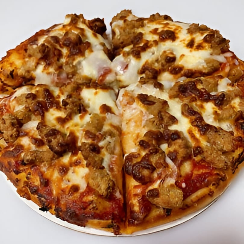 A close-up of a JNR's pizza with melted cheese and generous sausage toppings, cut into slices.