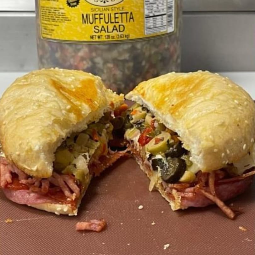 A JNR's muffuletta sandwich, cut in half, revealing layers of meat, cheese, and olive salad.